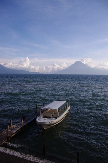 A boat rocks on the choppy waters of Lake Atitlan as it faces the shadow of the nearby volcano.